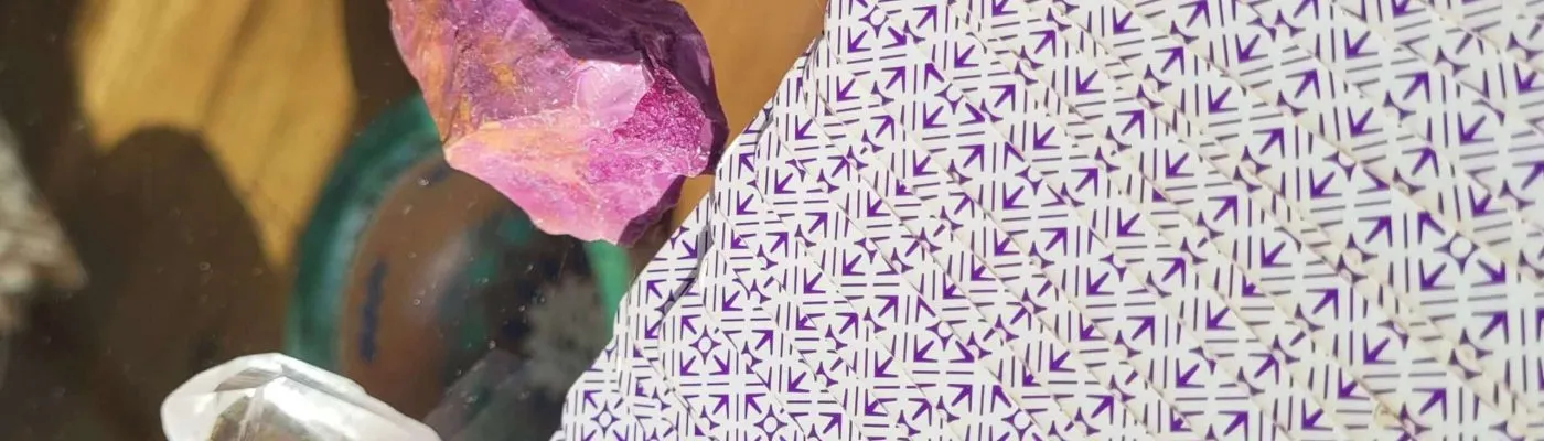 Verso das cartas do Tarot de Marselha em leque ao lado de um cristal